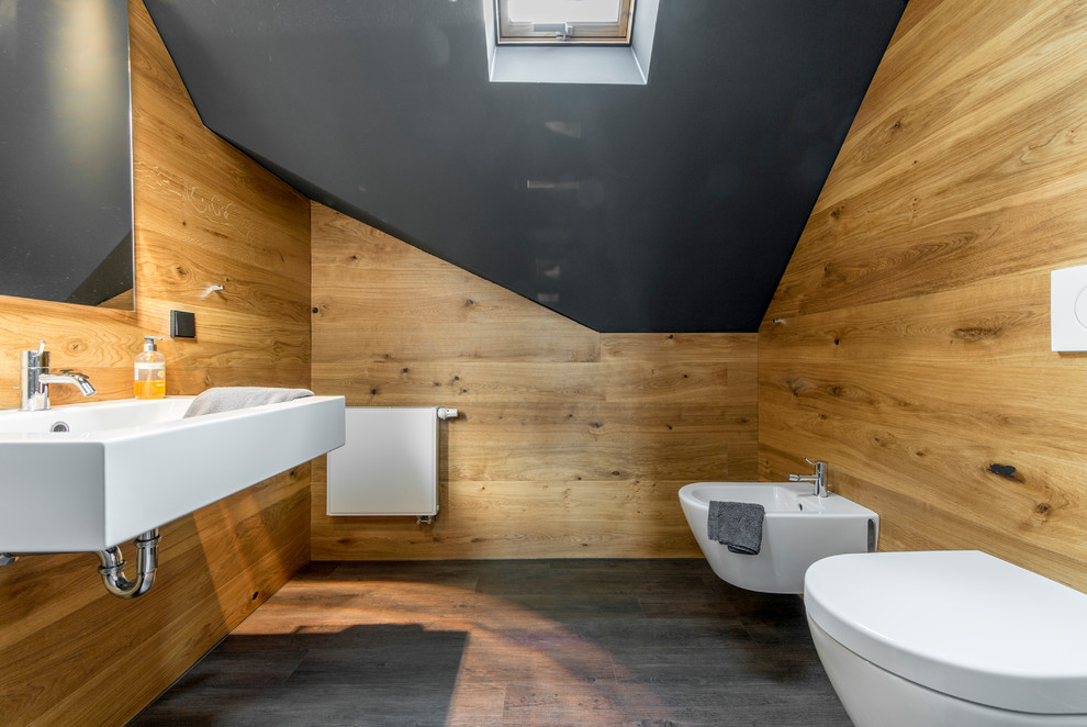 Small contemporary powder room in Essen with a two-piece toilet, brown walls, dark hardwood floors, a wall-mount sink and brown floor.