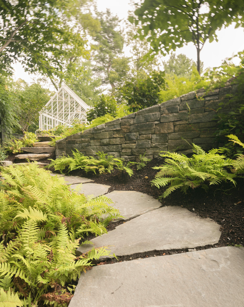 This is an example of a contemporary backyard garden in Boston with a retaining wall and natural stone pavers.