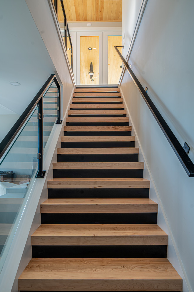На фото: лестница среднего размера в современном стиле с деревянными ступенями, крашенными деревянными подступенками и стеклянными перилами