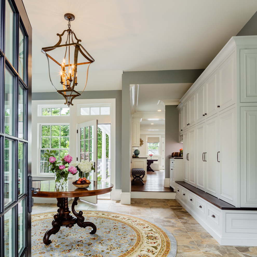 Photo of a large traditional mudroom in Boston with a single front door, grey walls, a glass front door and brown floor.