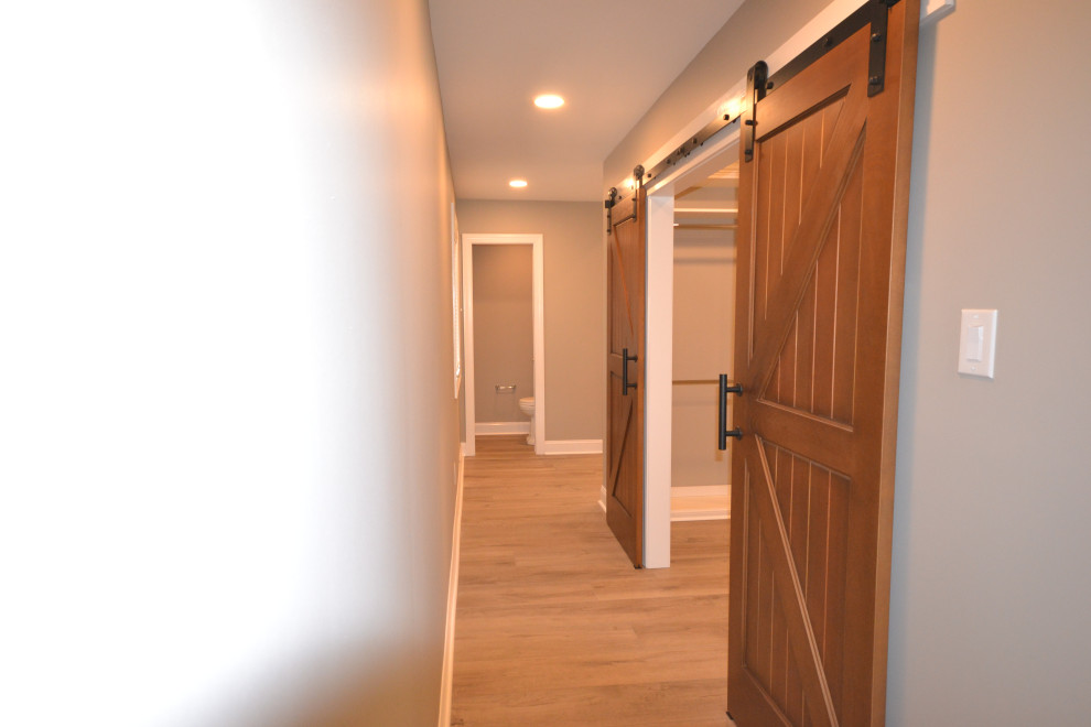 Photo of a large transitional gender-neutral walk-in wardrobe in Philadelphia with vinyl floors and brown floor.