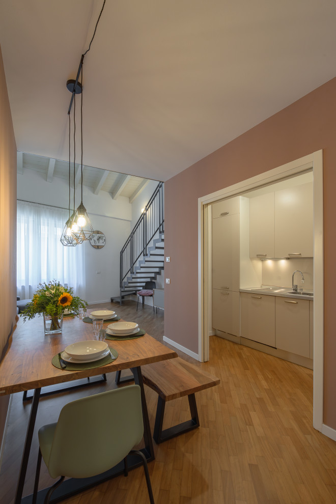 Idée de décoration pour une petite salle à manger nordique avec un mur rose et un sol en bois brun.