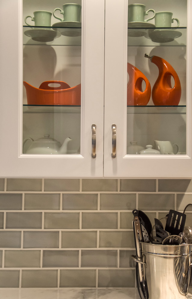 Mid-sized transitional u-shaped medium tone wood floor and brown floor eat-in kitchen photo in Bridgeport with a farmhouse sink, recessed-panel cabinets, white cabinets, marble countertops, gray backsplash, subway tile backsplash, stainless steel appliances and a peninsula