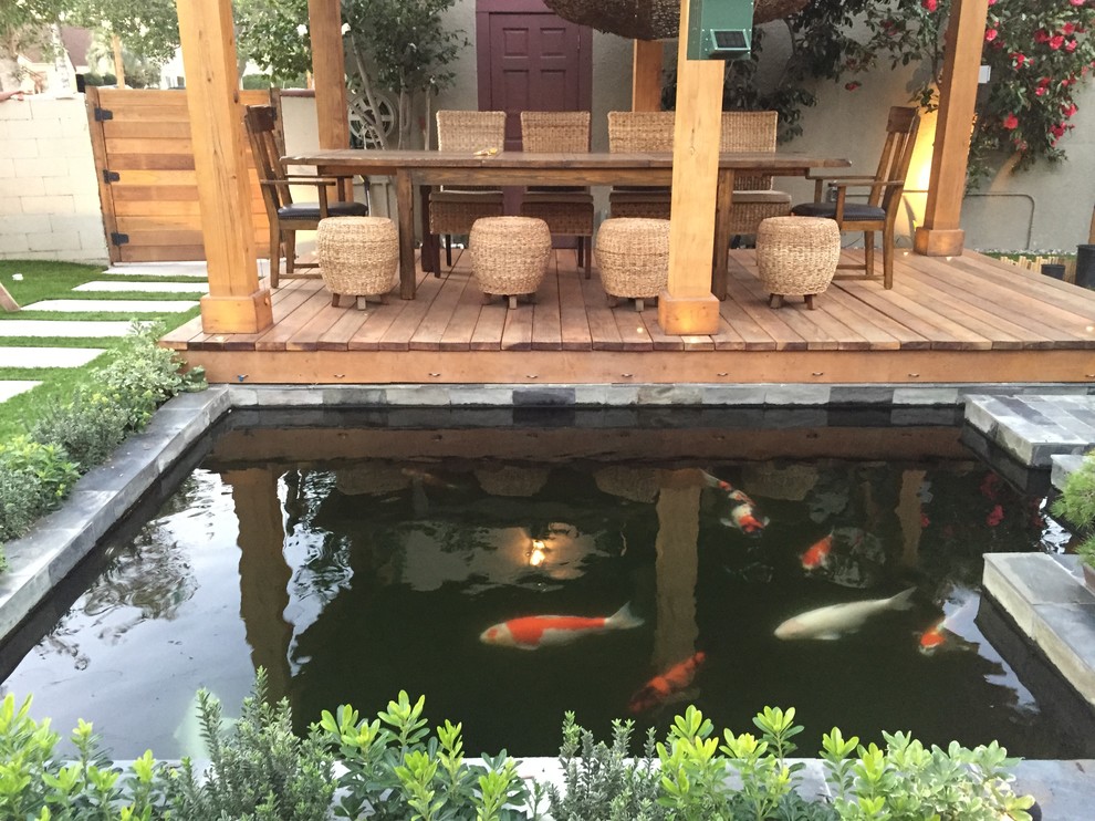 Inspiration for a mid-sized asian backyard patio fountain remodel in Los Angeles with decking and a pergola