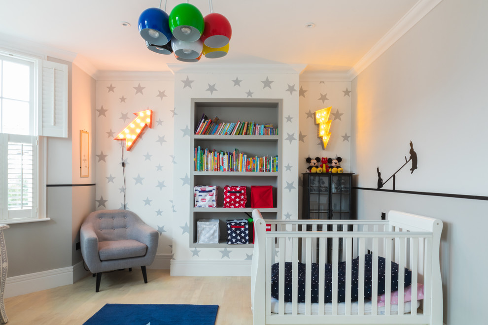 This is an example of a transitional gender-neutral nursery in London with grey walls, light hardwood floors and beige floor.