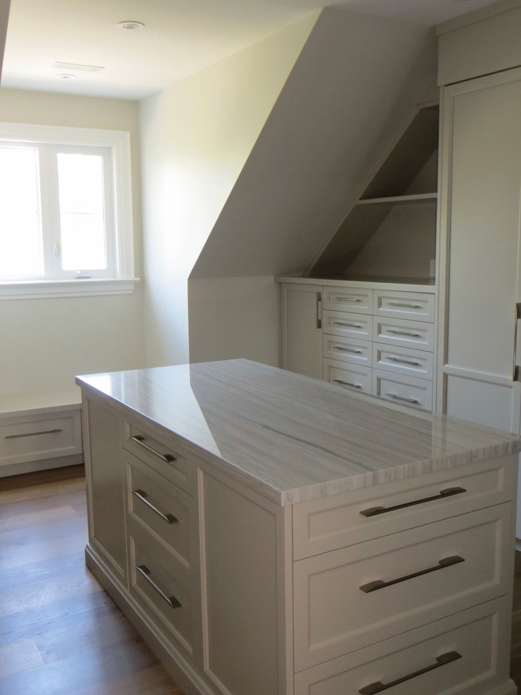 Inspiration for an expansive transitional gender-neutral walk-in wardrobe in Toronto with shaker cabinets, white cabinets and light hardwood floors.