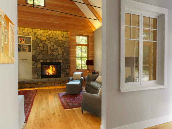 This is an example of a mid-sized country enclosed family room in Boston with grey walls, medium hardwood floors, a standard fireplace and a stone fireplace surround.