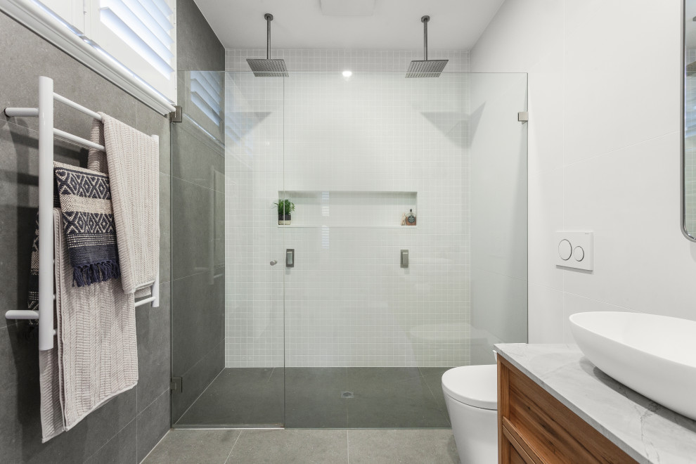 Design ideas for a mid-sized contemporary bathroom in Melbourne with a double shower, a wall-mount toilet, marble, white walls, ceramic floors, marble benchtops, grey floor, a hinged shower door, a niche, a single vanity and a floating vanity.