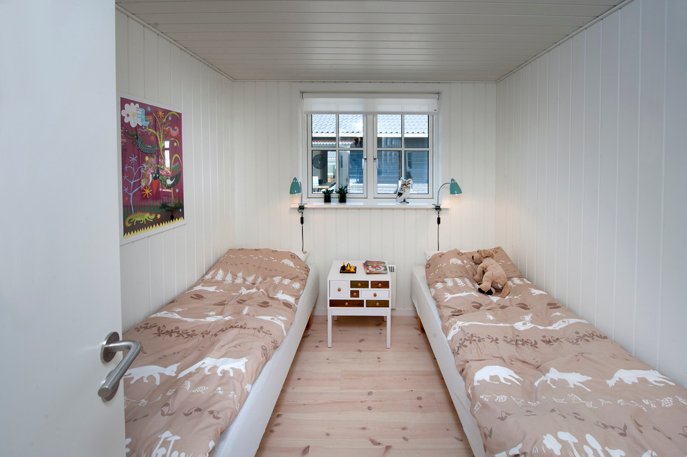 Design ideas for a small scandinavian gender-neutral kids' bedroom for kids 4-10 years old in Odense with white walls and light hardwood floors.