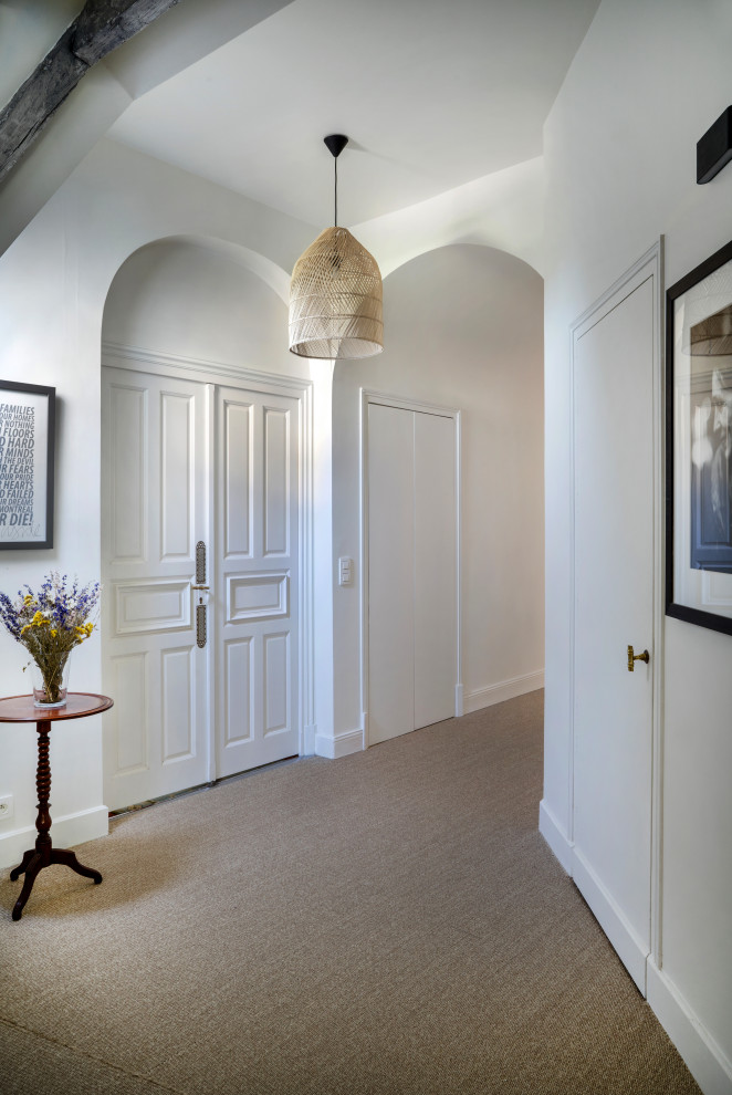 Cette photo montre un couloir tendance avec un mur blanc, un sol beige et un plafond voûté.