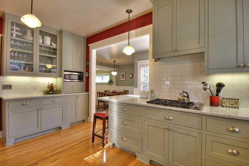This is an example of an arts and crafts separate kitchen in San Francisco with shaker cabinets, green cabinets, marble benchtops, white splashback, subway tile splashback, stainless steel appliances and medium hardwood floors.