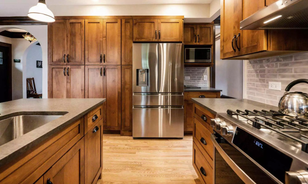 Eat-in kitchen - small rustic galley medium tone wood floor and brown floor eat-in kitchen idea with a drop-in sink, flat-panel cabinets, dark wood cabinets, gray backsplash, glass tile backsplash, stainless steel appliances, an island and gray countertops