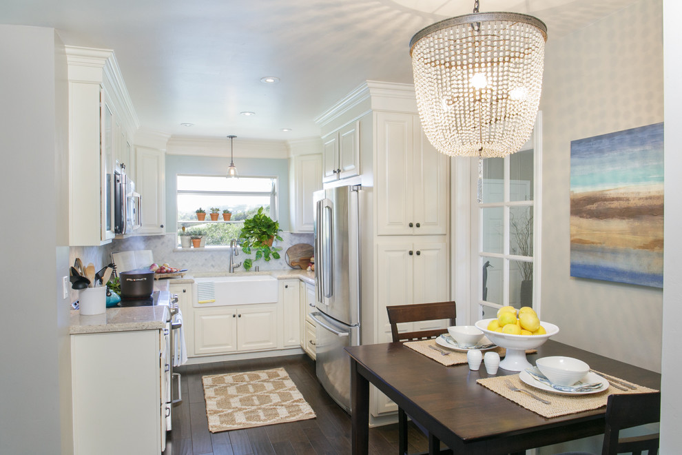 Photo of a small transitional u-shaped eat-in kitchen in San Diego with a farmhouse sink, white cabinets, white splashback, mosaic tile splashback, stainless steel appliances, dark hardwood floors, no island, raised-panel cabinets, quartz benchtops, brown floor and white benchtop.