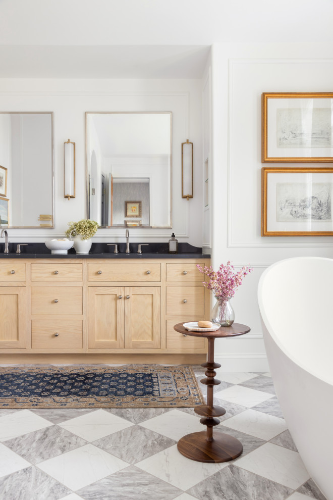 Пример оригинального дизайна: большая главная ванная комната в стиле неоклассика (современная классика) с фасадами в стиле шейкер, светлыми деревянными фасадами, отдельно стоящей ванной, душем в нише, унитазом-моноблоком, белой плиткой, керамической плиткой, белыми стенами, полом из керамогранита, врезной раковиной, столешницей из искусственного кварца, белым полом, душем с распашными дверями, черной столешницей, нишей, тумбой под две раковины, встроенной тумбой, сводчатым потолком и панелями на части стены