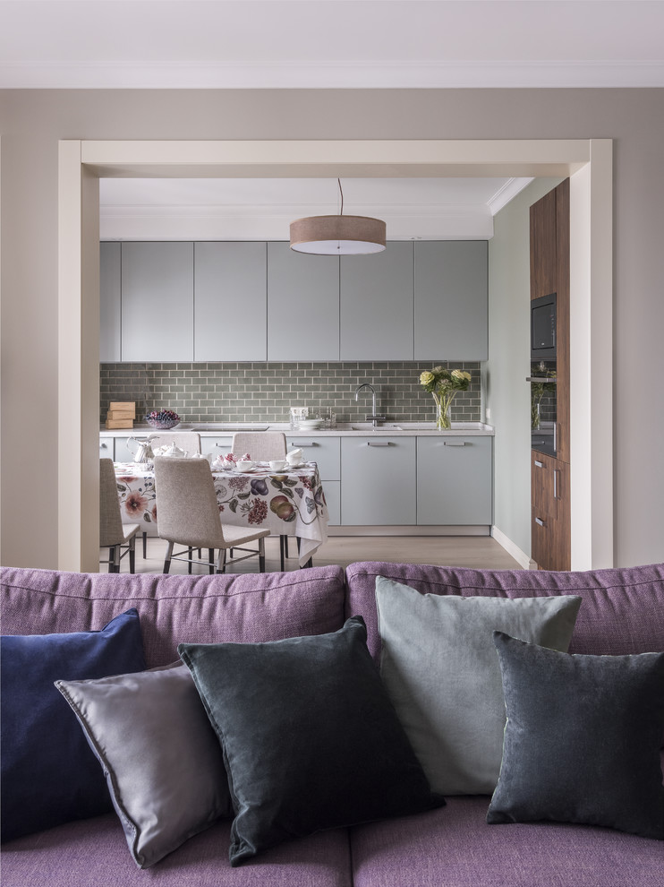 Design ideas for a mid-sized transitional single-wall open plan kitchen in Moscow with flat-panel cabinets, green cabinets, quartz benchtops, green splashback, ceramic splashback, light hardwood floors, no island, an integrated sink, black appliances, beige floor and beige benchtop.