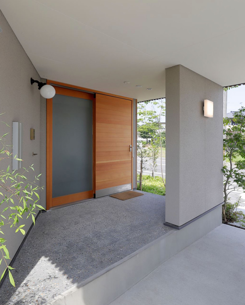 Aménagement d'une porte d'entrée de taille moyenne avec un mur gris, une porte coulissante, une porte en bois brun, un sol gris et un plafond en lambris de bois.