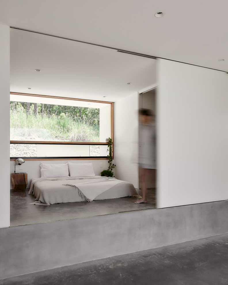 Ispirazione per una piccola camera matrimoniale minimalista con pareti bianche, pavimento in cemento e pavimento grigio