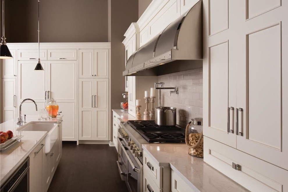 Example of a mid-sized transitional galley dark wood floor open concept kitchen design in Omaha with a farmhouse sink, recessed-panel cabinets, white cabinets, granite countertops, white backsplash, ceramic backsplash, stainless steel appliances and an island