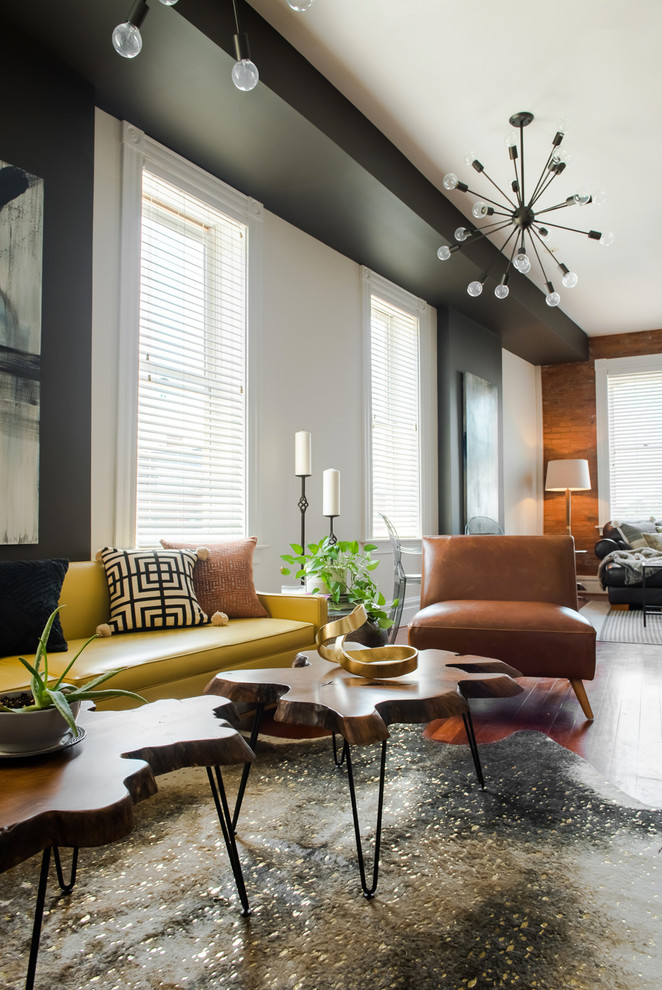 This is an example of a mid-sized transitional open concept living room in St Louis with grey walls, medium hardwood floors, a two-sided fireplace, a wood fireplace surround, a wall-mounted tv and brown floor.