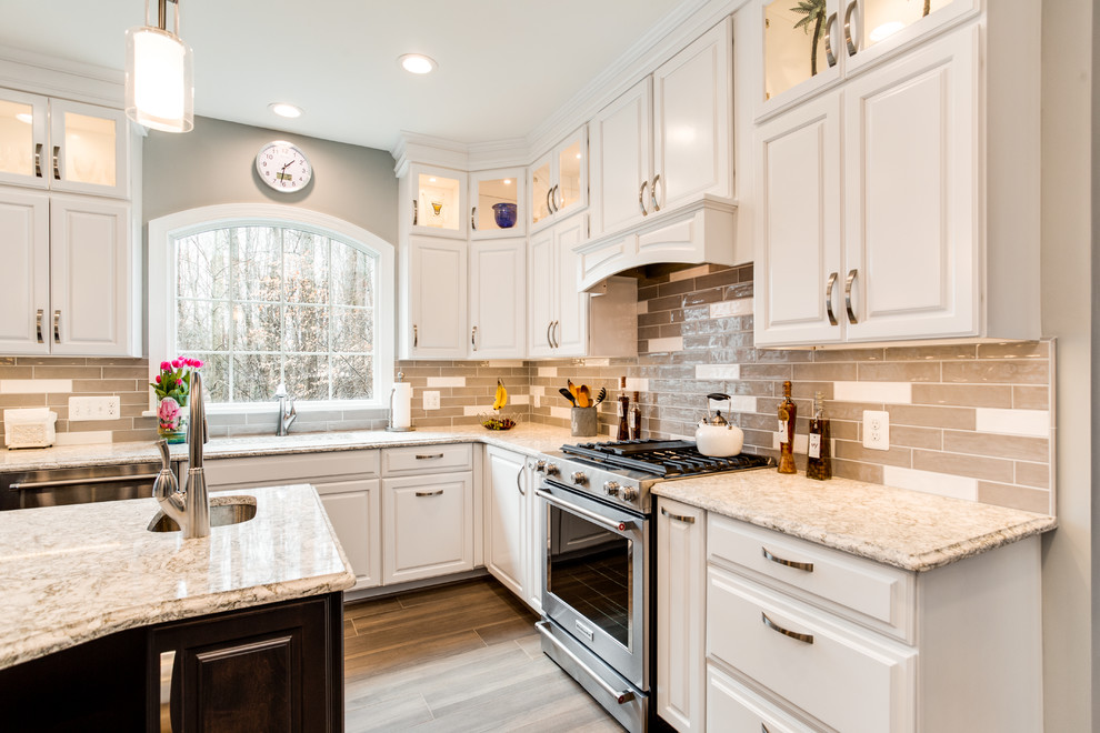 Example of a large transitional u-shaped porcelain tile and brown floor eat-in kitchen design in DC Metro with a single-bowl sink, raised-panel cabinets, white cabinets, quartz countertops, gray backsplash, ceramic backsplash, stainless steel appliances and an island