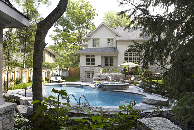 This is an example of a large contemporary backyard custom-shaped natural pool in Toronto with a water feature and brick pavers.
