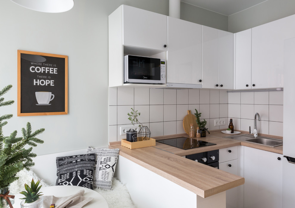 Design ideas for a small scandinavian u-shaped eat-in kitchen in Other with a drop-in sink, flat-panel cabinets, white cabinets, white splashback, a peninsula, beige benchtop and wood benchtops.