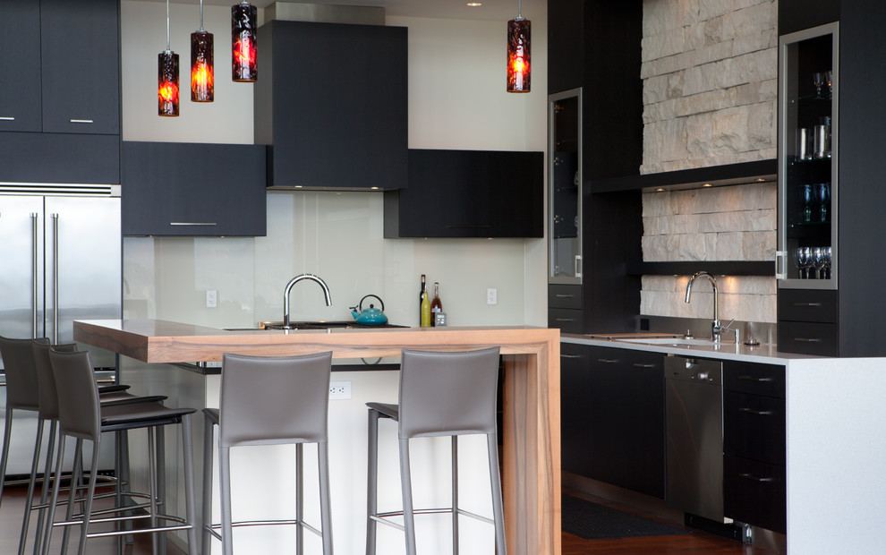 This is an example of a large contemporary galley kitchen in Vancouver with an undermount sink, flat-panel cabinets, dark wood cabinets, granite benchtops, beige splashback, stone tile splashback and dark hardwood floors.