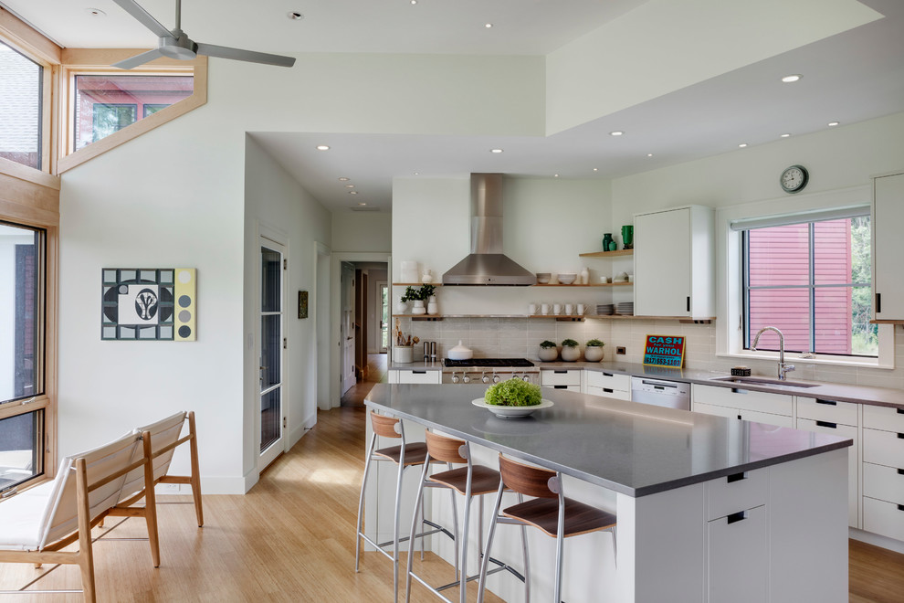 Inspiration for a contemporary l-shaped eat-in kitchen in Boston with an undermount sink, flat-panel cabinets, white cabinets, grey splashback, stainless steel appliances, bamboo floors, with island, brown floor and grey benchtop.