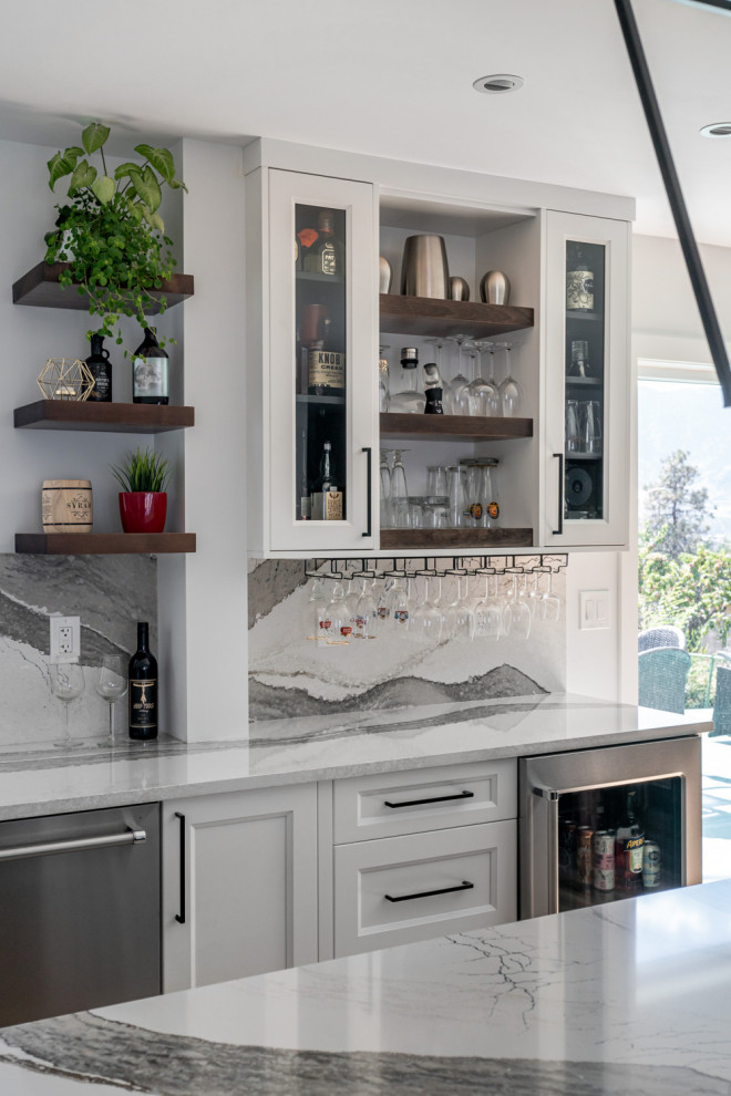 Example of a mid-sized transitional u-shaped medium tone wood floor and brown floor eat-in kitchen design with an undermount sink, recessed-panel cabinets, white cabinets, quartz countertops, white backsplash, stone slab backsplash, stainless steel appliances, an island and white countertops