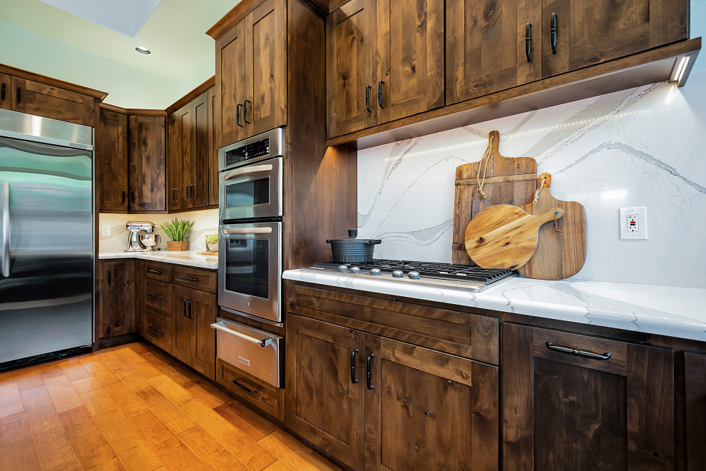 Example of a large transitional u-shaped open concept kitchen design in Phoenix with a farmhouse sink, shaker cabinets, dark wood cabinets, quartz countertops, white backsplash, quartz backsplash, stainless steel appliances, an island and white countertops