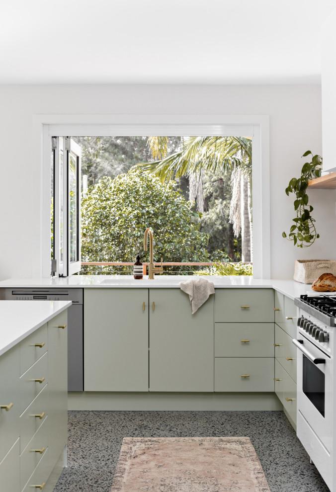 Inspiration for a mid-sized beach style l-shaped open plan kitchen in Central Coast with an undermount sink, flat-panel cabinets, green cabinets, quartz benchtops, white splashback, terra-cotta splashback, white appliances, concrete floors, with island, grey floor and white benchtop.