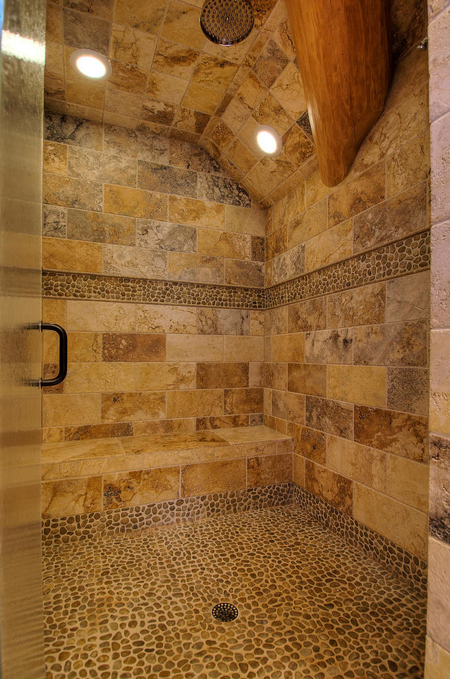 Inspiration for a mid-sized country 3/4 bathroom in Denver with a corner shower, brown tile, stone tile, brown walls, pebble tile floors, beige floor and a hinged shower door.