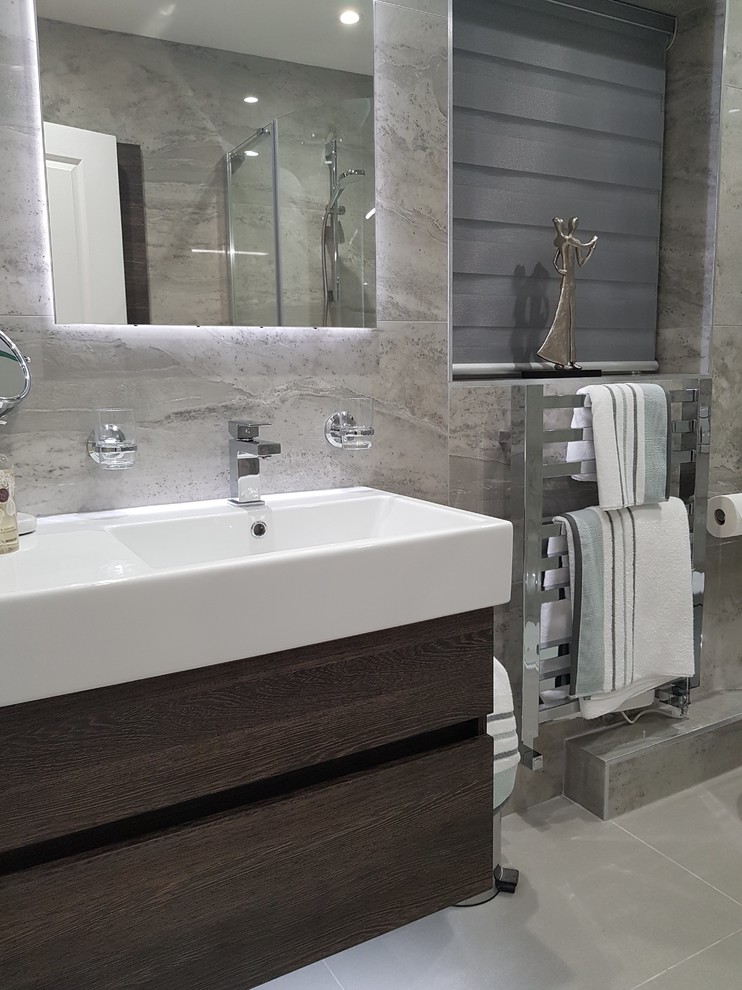 Photo of a medium sized contemporary ensuite bathroom in Other with flat-panel cabinets, dark wood cabinets, a corner shower, a wall mounted toilet, grey tiles, porcelain tiles, grey walls, porcelain flooring, a wall-mounted sink, grey floors and a hinged door.