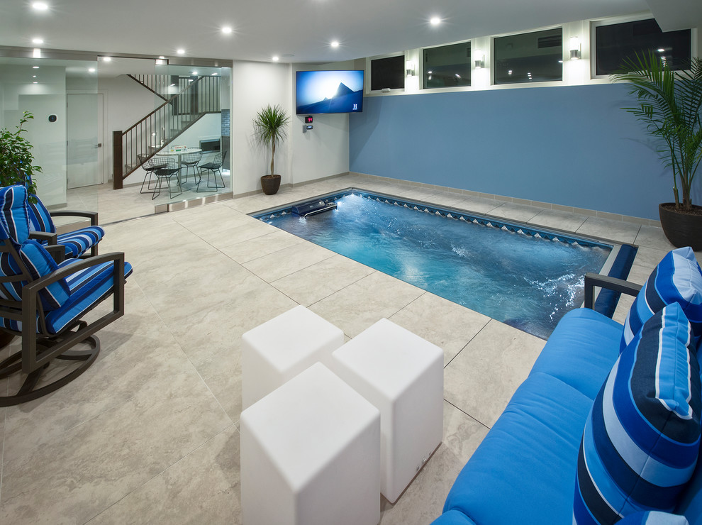 This is an example of a mid-sized modern indoor custom-shaped pool in Calgary with a pool house and tile.