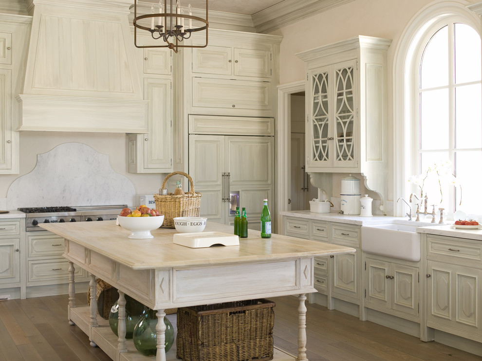 Design ideas for a large l-shaped eat-in kitchen in Atlanta with a farmhouse sink, glass-front cabinets, distressed cabinets, marble benchtops, white splashback, stone tile splashback, stainless steel appliances, light hardwood floors and with island.