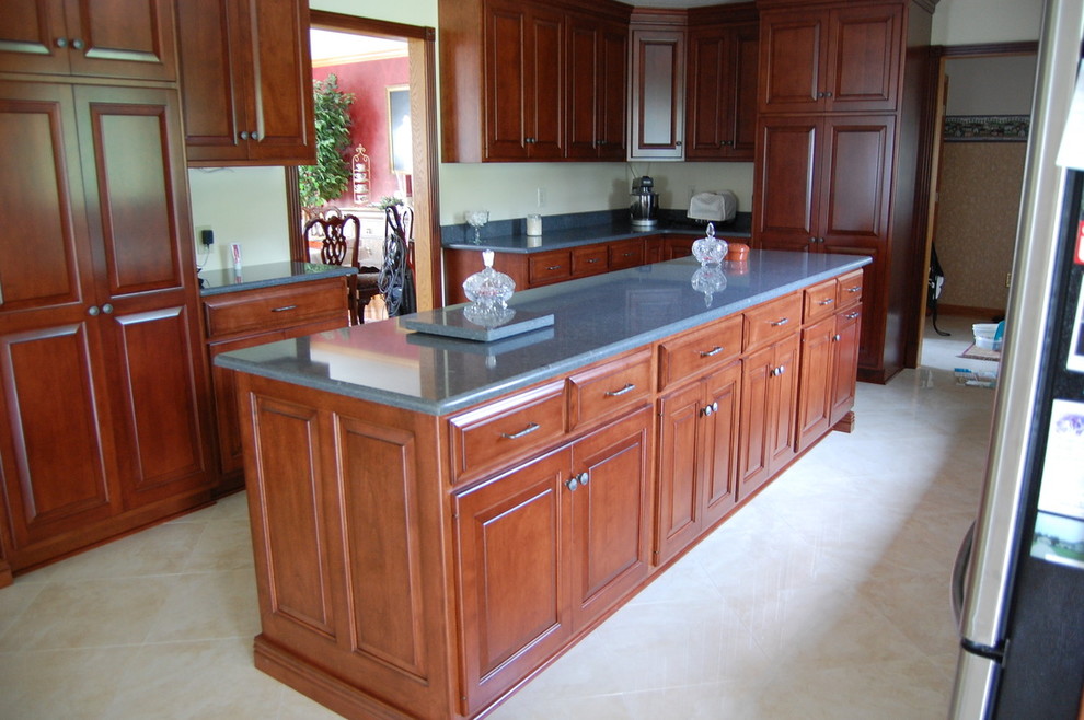 Transitional marble floor enclosed kitchen photo with raised-panel cabinets, medium tone wood cabinets, granite countertops, beige backsplash, subway tile backsplash, stainless steel appliances and an island