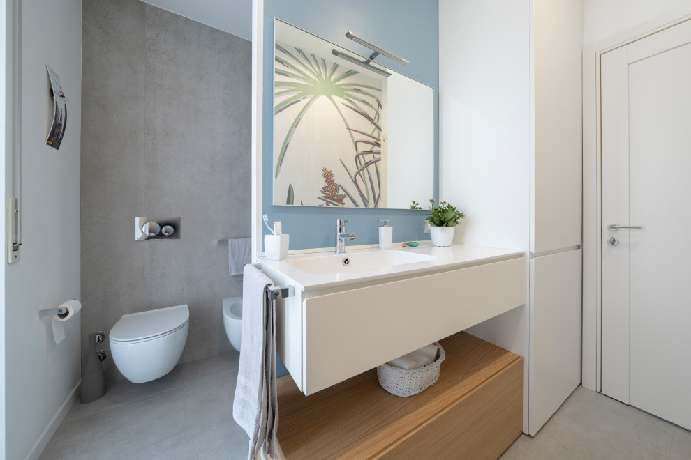 Design ideas for a large modern 3/4 bathroom in Milan with flat-panel cabinets, white cabinets, an alcove shower, a two-piece toilet, gray tile, porcelain tile, multi-coloured walls, porcelain floors, an integrated sink, engineered quartz benchtops, grey floor, a hinged shower door and white benchtops.