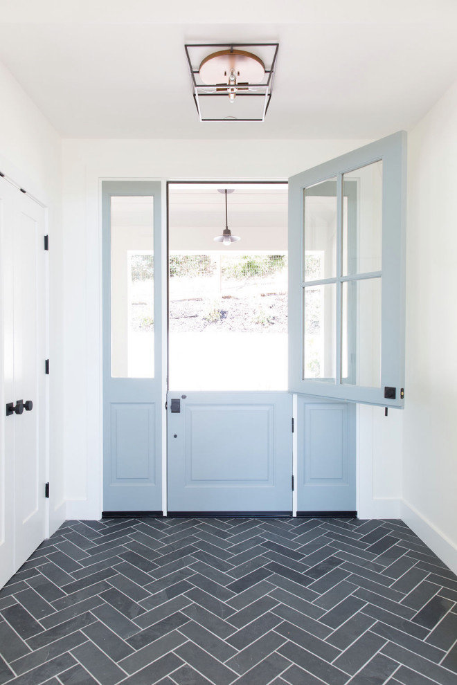 Photo of a large transitional entry hall in San Francisco with white walls, porcelain floors, a single front door, a blue front door and black floor.