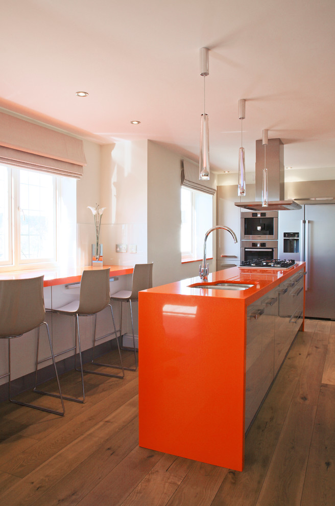This is an example of a mid-sized contemporary galley separate kitchen in London with flat-panel cabinets, beige cabinets, an undermount sink, quartz benchtops and stainless steel appliances.