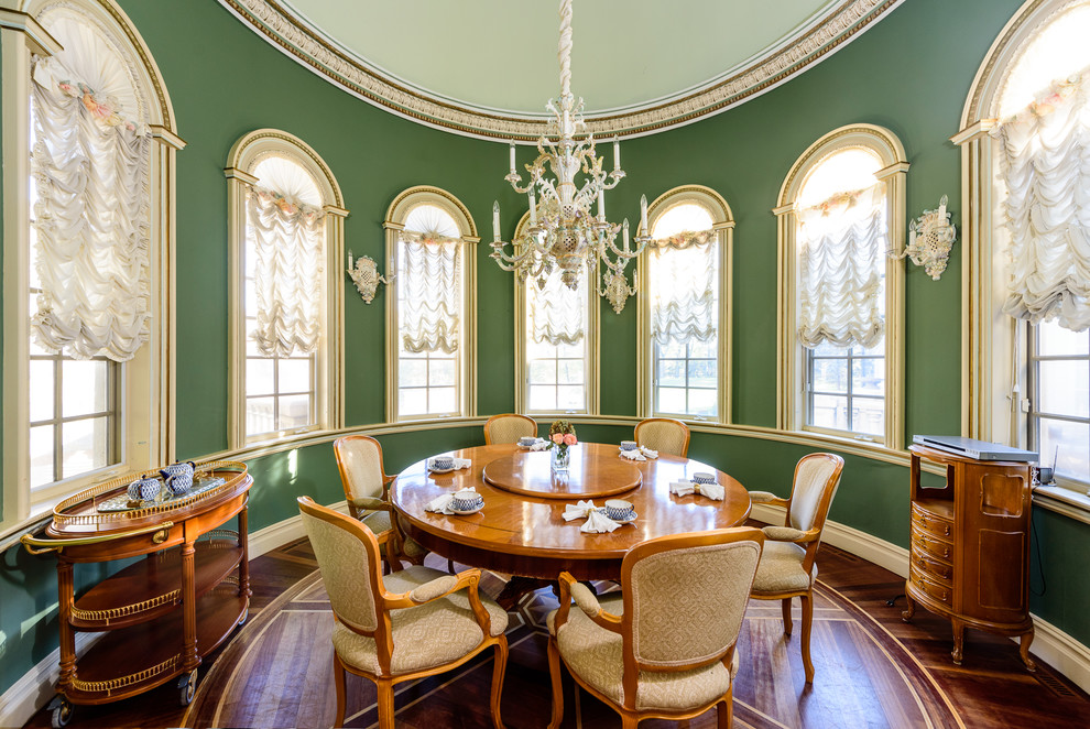 This is an example of a traditional separate dining room in New York with green walls, medium hardwood floors and brown floor.