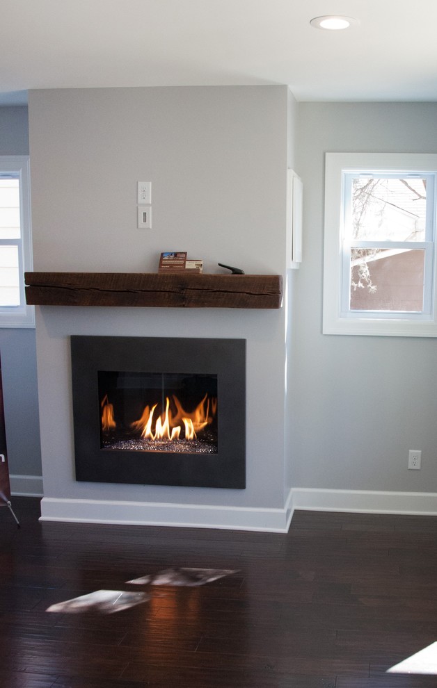 Photo of a large transitional enclosed living room in Minneapolis with grey walls, dark hardwood floors, a standard fireplace, a metal fireplace surround and a wall-mounted tv.