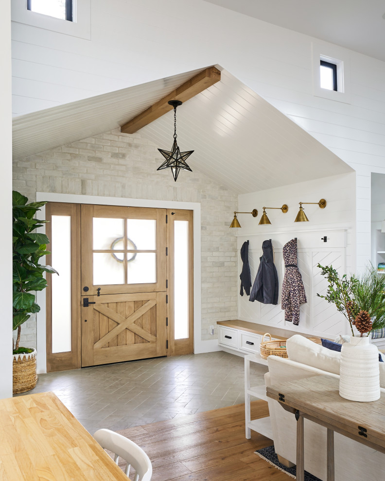This is an example of a large country mudroom in Orange County with white walls, limestone floors, a dutch front door, a light wood front door, green floor, timber and planked wall panelling.