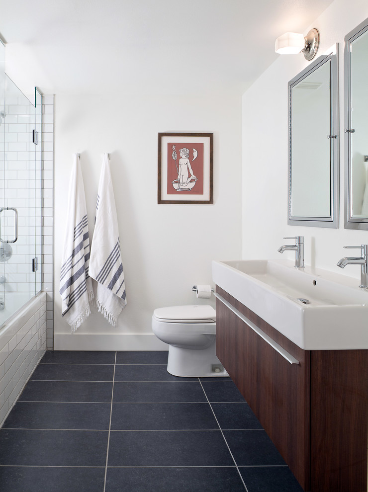 Design ideas for a large contemporary master bathroom in Denver with flat-panel cabinets, dark wood cabinets, an alcove tub, a shower/bathtub combo, white tile, subway tile, white walls, porcelain floors, a trough sink, grey floor and a hinged shower door.
