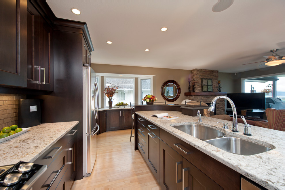 Inspiration for a large u-shaped light wood floor eat-in kitchen remodel in Vancouver with an undermount sink, recessed-panel cabinets, dark wood cabinets, glass tile backsplash, stainless steel appliances and an island