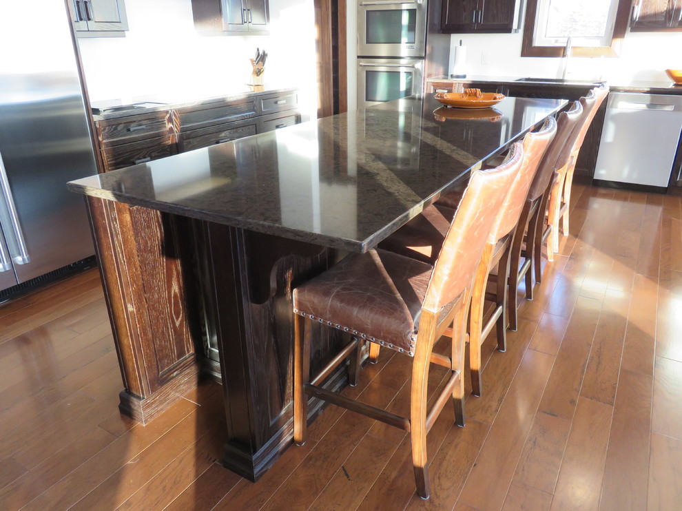 Open concept kitchen - large transitional l-shaped dark wood floor open concept kitchen idea with recessed-panel cabinets, dark wood cabinets, quartz countertops, stainless steel appliances, an island and an undermount sink
