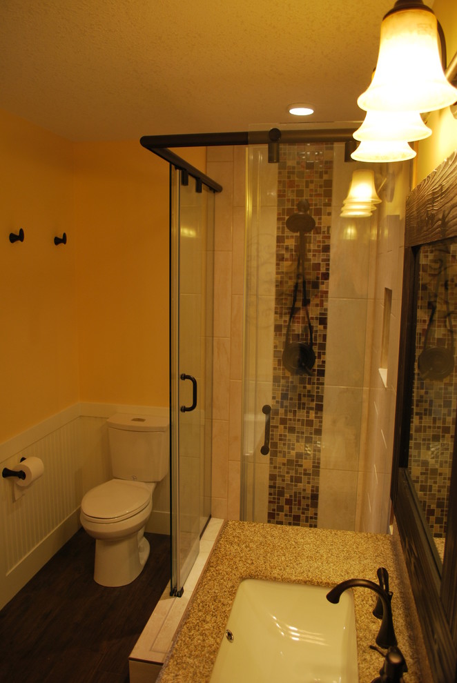 Mid-sized mountain style 3/4 multicolored tile and stone tile dark wood floor and brown floor freestanding bathtub photo in Calgary with a two-piece toilet, yellow walls, shaker cabinets, dark wood cabinets, an undermount sink and limestone countertops