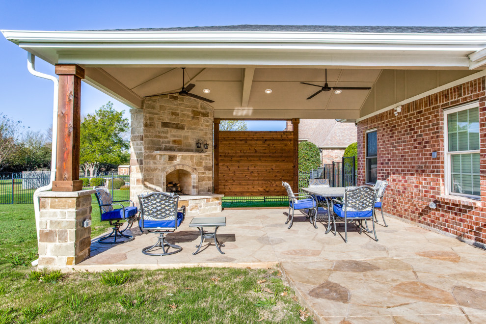 Large eclectic backyard verandah in Dallas with with fireplace, stamped concrete and a roof extension.