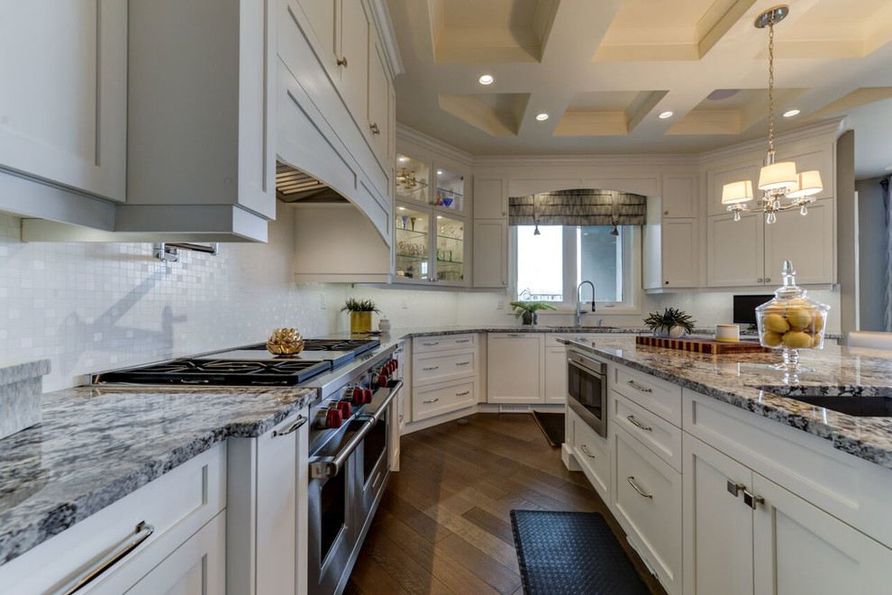 Kitchen - large transitional u-shaped medium tone wood floor and brown floor kitchen idea in Edmonton with shaker cabinets, white cabinets, granite countertops, white backsplash, an island, an undermount sink, glass tile backsplash and paneled appliances
