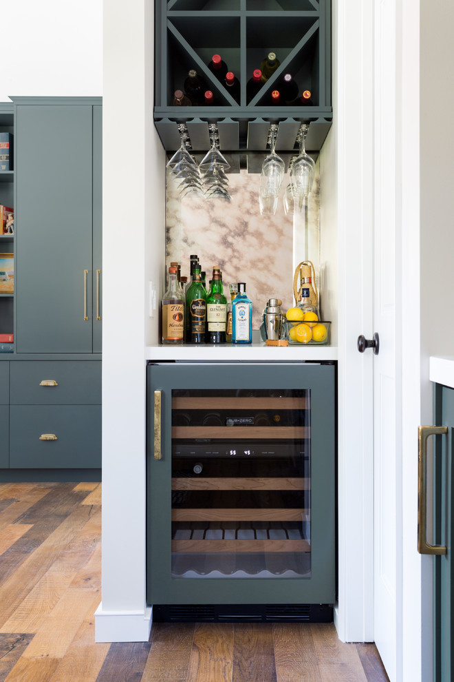 Inspiration for a small traditional single-wall home bar in Los Angeles with open cabinets, grey cabinets, quartzite benchtops, beige splashback, medium hardwood floors, brown floor and white benchtop.