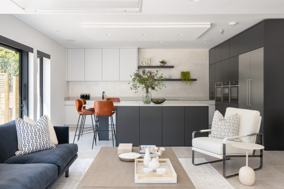 This is an example of a large contemporary grey and white l-shaped open plan kitchen in Gloucestershire with flat-panel cabinets, quartz worktops, grey splashback, engineered quartz splashback, porcelain flooring, an island, beige floors and grey worktops.